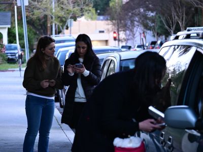 Homeless Services staff attempting to connect with a homeless individual living in their car as her colleagues have a discussion in the background. 